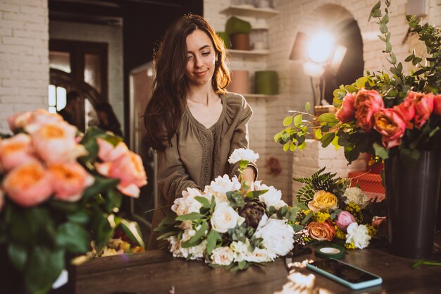 Woman florist at her own floral shop taking care of flowers