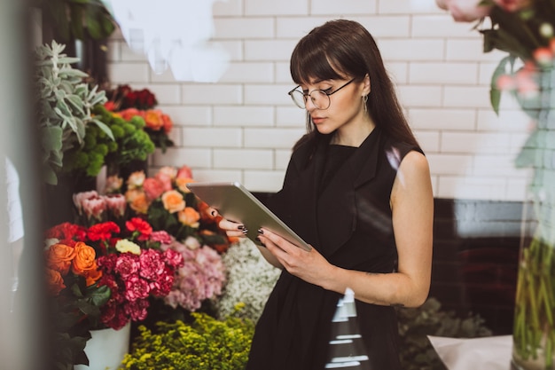 Woman florist at her own floral shop taking care of flowers