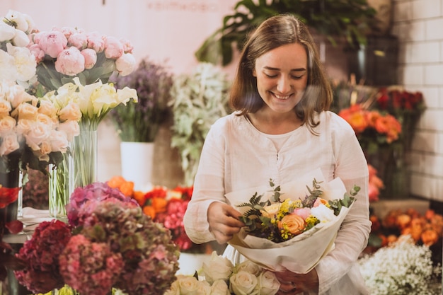 Woman florist at her own floral shop taking care of flowers