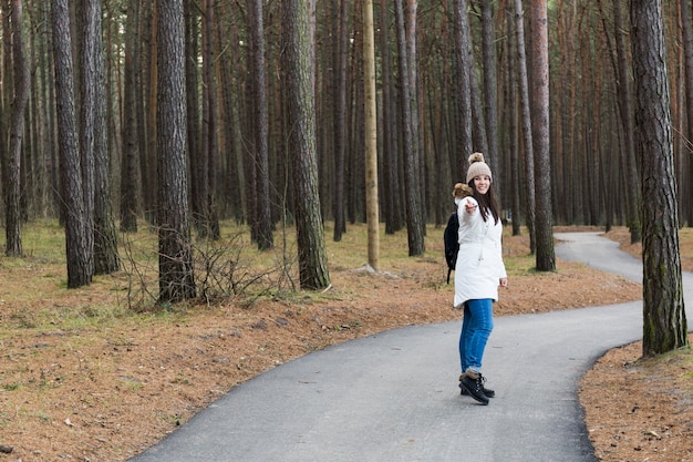 Free photo woman on forest path pointing at camera