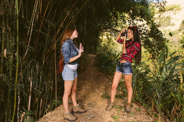 Woman gesturing while her friend taking photograph with camera