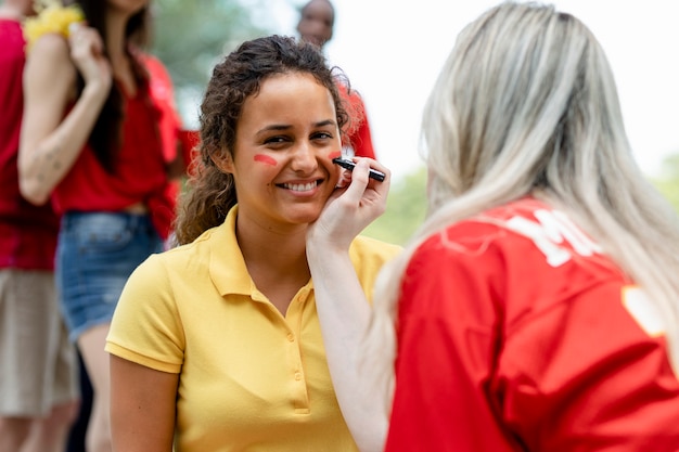 Free photo woman getting her cheeks painted with her team colors