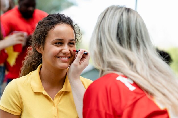 Woman getting her cheeks painted with her team colors