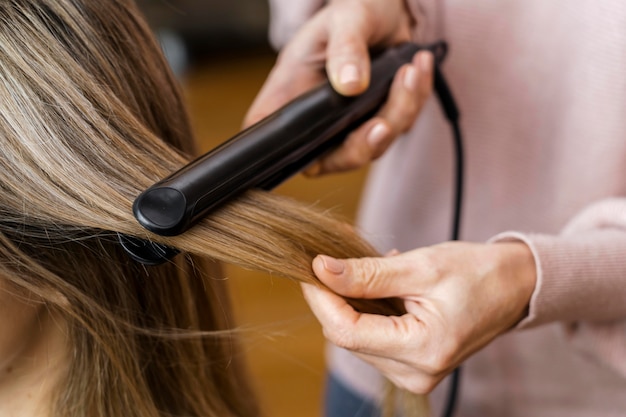 Free photo woman getting her hair straightened at home