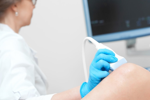 Free photo woman getting knee ultrasound scanning examination at the clinic