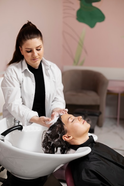 Woman getting treatment at hairdresser shop