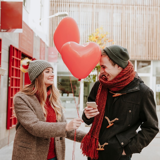 Woman gifting balloons to man with smartphone