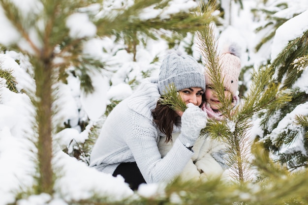 Free Photo woman and girl hiding behind spruce