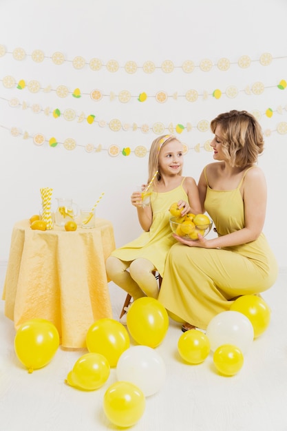 Free Photo woman and girl posing while holding lemons