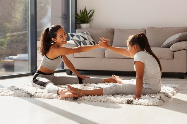 Woman and girl stretching together indoors