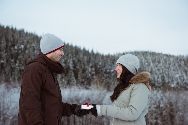 Woman giving gift to man on snow covered mountain