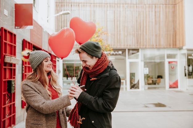 Woman giving heart balloons to smiling boyfriend