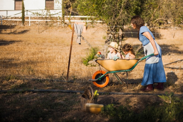 Woman giving her children ride in wheelbarrow