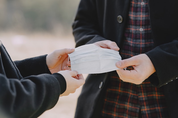 Woman giving protective mask to a man