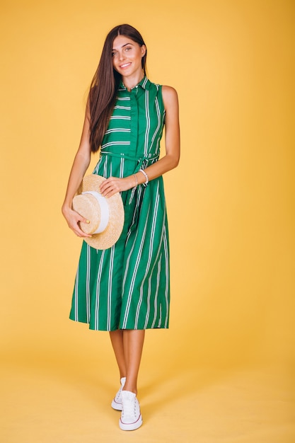 Free photo woman in green dress and hat on yellow background