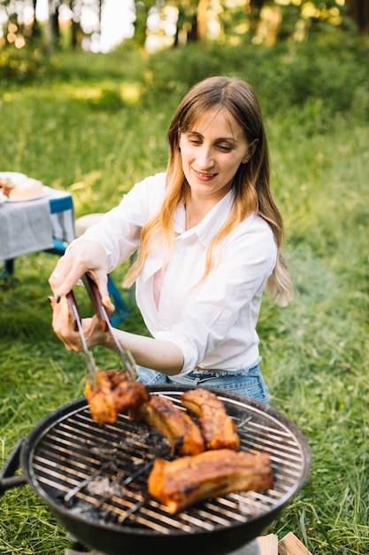 Free Photo woman grilling meat in nature