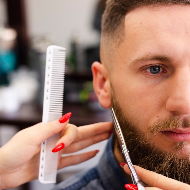 Woman grooming a client's beard