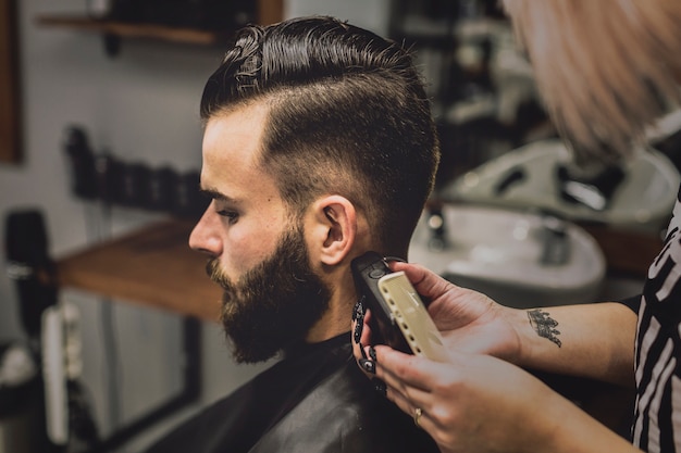 Woman grooming customer in barbershop