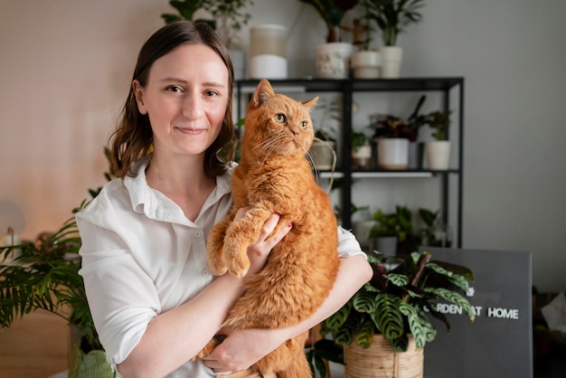 Free photo woman growing plants at home holding cat