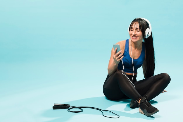 Woman in gym outfit enjoying music in headphones with jumping rope