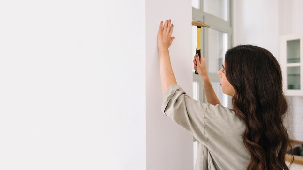 Woman hammering nail to wall