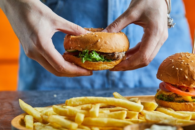 A woman hand holding cheeseburger with fry potato, ketchup, mayonnaise 