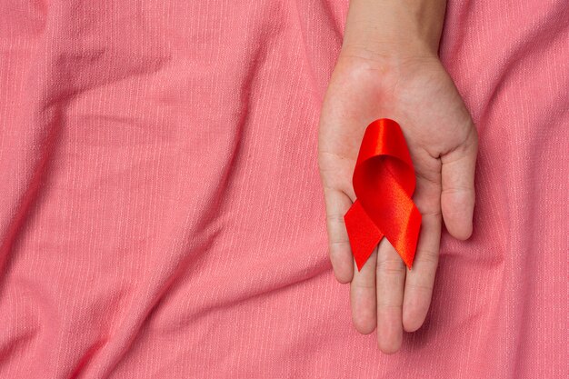 Woman hand holding red ribbon HIV awareness concept World AIDS Day and World Sexual Health Day.