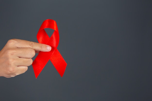 Woman hand holding red ribbon HIV awareness concept World AIDS Day and World Sexual Health Day.