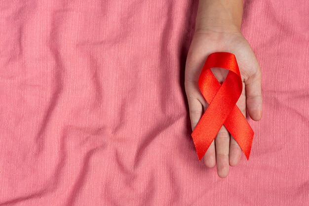 Free photo woman hand holding red ribbon hiv awareness concept world aids day and world sexual health day.