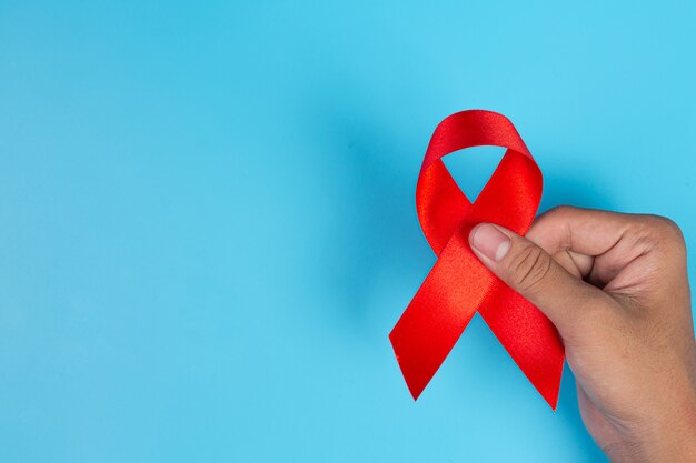 Woman hand holding red ribbon HIV awareness concept World AIDS Day and World Sexual Health Day.