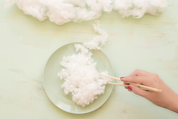 Free Photo woman hand holding white cloud with chopsticks