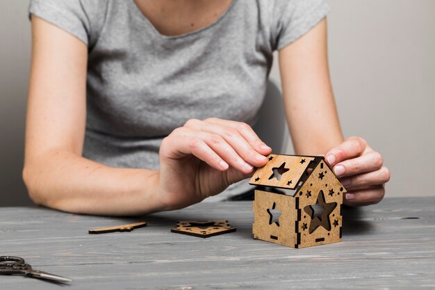 Woman hand making creative small house on wooden table