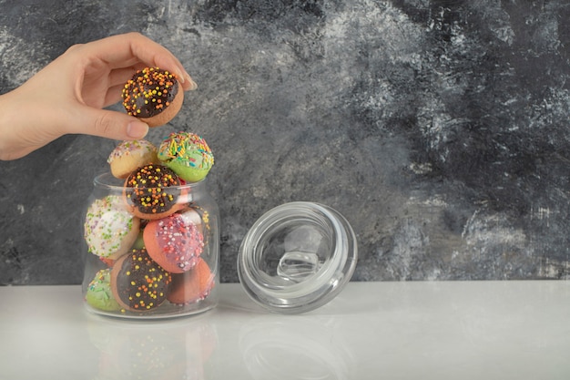 Free Photo woman hand taking a doughnut from a glass jar. 