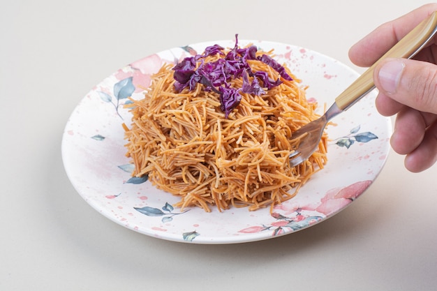 Woman hand taking spaghetti from the plate with fork.