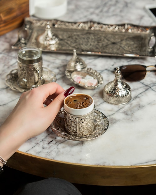 Free photo woman hand next to turkish coffee served with water in turkish silver set