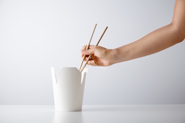 Free photo woman hand uses chopsticks to pick up tasty noodles from takeaway blank box isolated on white retail set presentation