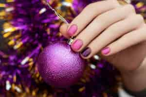 Free photo woman hand with christmas and new year nail design hold glittering toy sphere