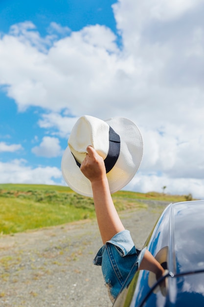 Free photo woman hand with hat against sky