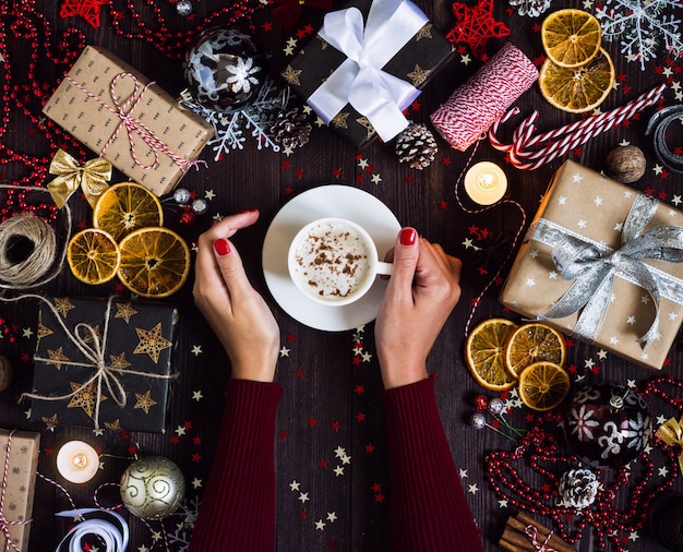 Free photo woman hands holding coffee cup drink christmas holiday gift box on decorated festive table