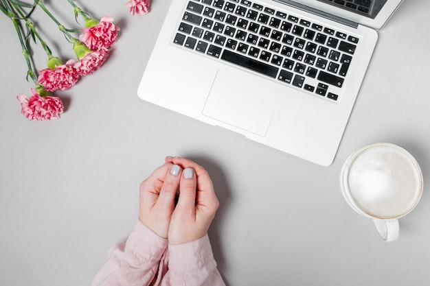 Free Photo woman hands with coffee and laptop flowers carnations on white background spring work space background top view