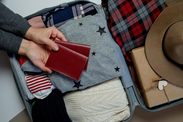 Free photo woman hands with passports on the background open suitcase packed for travelling winter vacations and holidays top view