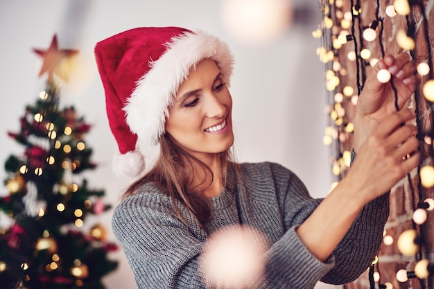 Free photo woman hanging christmas lights at home