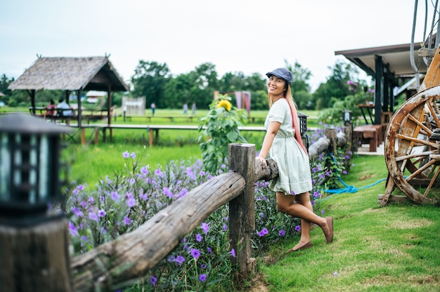 Free photo woman happily stand in the flower garden in the wooden railings