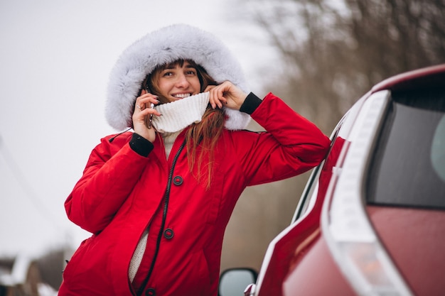 Free photo woman happy talking on the phone outside by car in winter