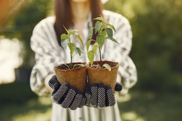 Woman in a hat holding flowerpots