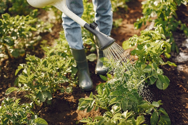 Woman in a hat holding funnel and works in a garden