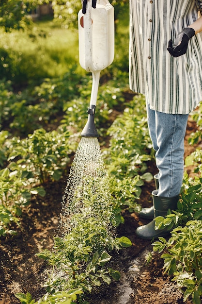 Free photo woman in a hat holding funnel and works in a garden