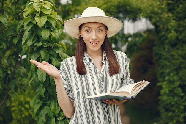 Woman in a hat with a book in a garden