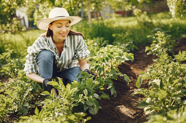 Woman in a hat working in a garden