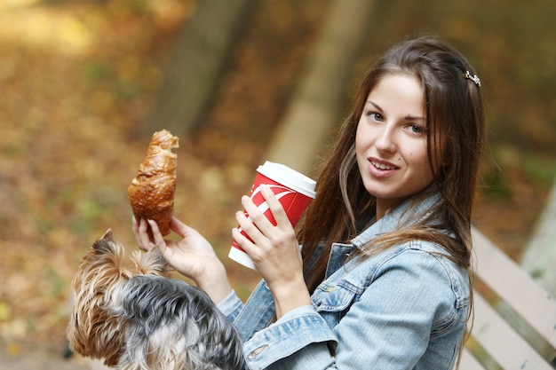 Woman have lunch while strolling with her dog